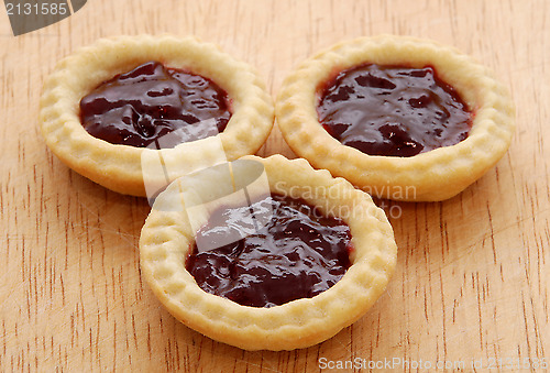 Image of Three tasty jam tarts on a wooden table