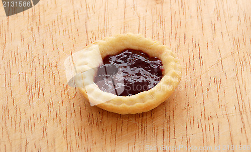 Image of Single tasty jam tart on a wooden table