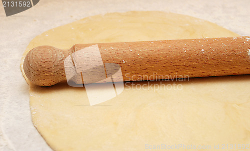 Image of Fresh pastry rolled out with a wooden rolling pin