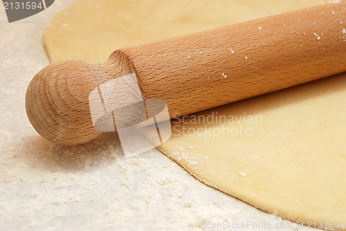 Image of Detail of a wooden rolling pin on rolled out pastry