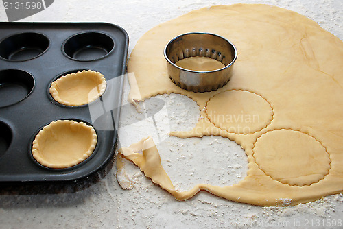 Image of Pastry circles being cut and filling a bun tin to make jam tarts