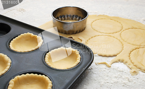 Image of Pastry circles cut and lining a metal bun tin