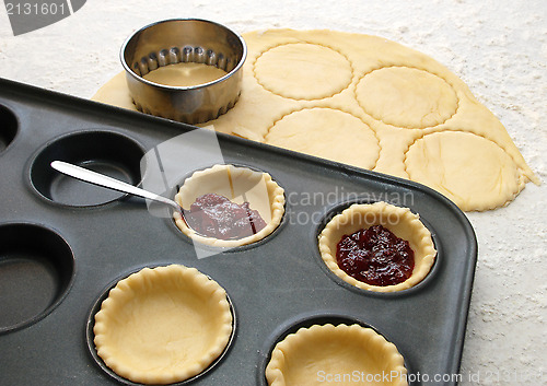 Image of Cutting and filling pastry shapes to make jam tarts 