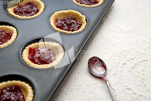 Image of Filled, uncooked jam tarts in a tin