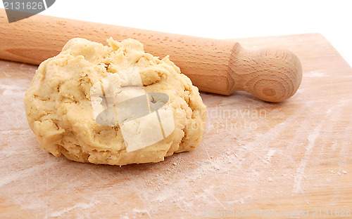 Image of Wooden rolling pin and a fresh ball of pastry on a floured board