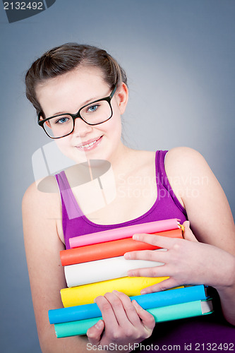 Image of Silly smiling schoolgirl with glasses and lots of books