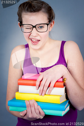 Image of Silly smiling schoolgirl with glasses and lots of books