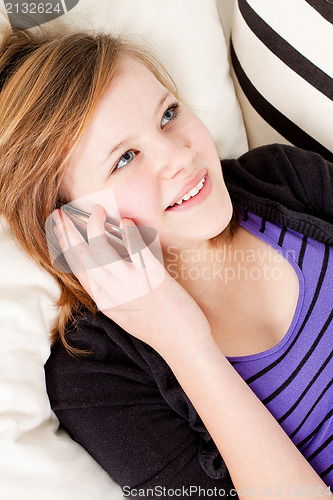Image of teenager girl smiling and lying on couch with mobile phone