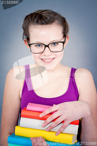 Image of Silly smiling schoolgirl with glasses and lots of books