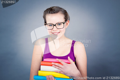 Image of Silly smiling schoolgirl with glasses and lots of books