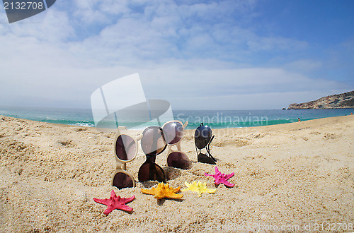 Image of Four pairs of sunglasses on the beach 