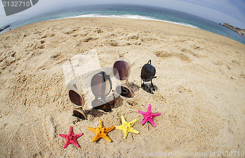 Image of Four pairs of sunglasses on the beach 
