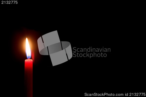 Image of burning red candle with black background