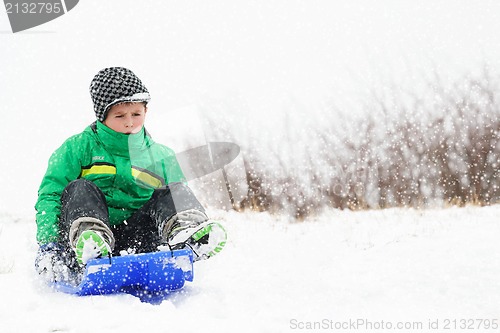 Image of A young boy shows his excitement sledding down a hill in winter