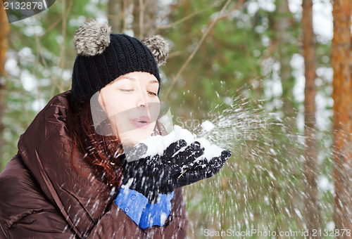 Image of Cute young woman playing with snow  outdoors