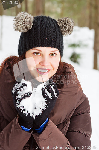 Image of Cute young woman playing with snow  outdoors