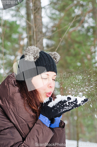 Image of Cute young woman playing with snow  outdoors