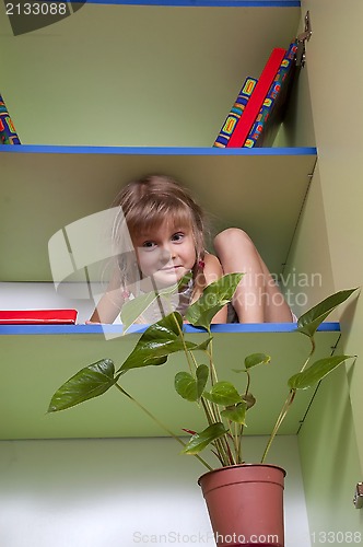 Image of 	playful little girl hiding on the shelf