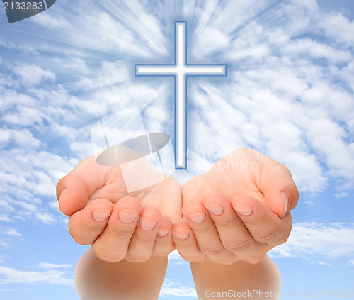 Image of Hands holding Christian cross with light beams