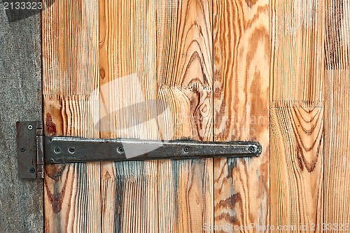 Image of Detail of wooden door with a metal hinge