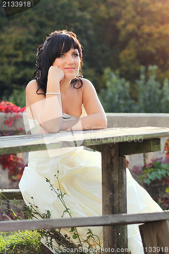 Image of Girl in the wedding dress sitting on the bench