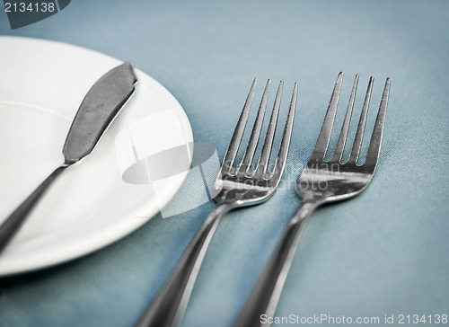 Image of Served restaurant table with forks, white plate and knife