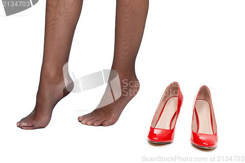 Image of Tired female legs on a white background next to the red shoes