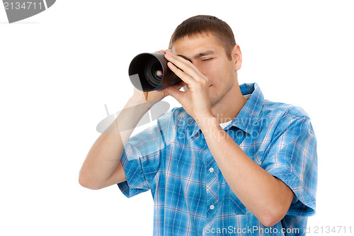 Image of Handsome young man holding camera lens like it was spyglass on w