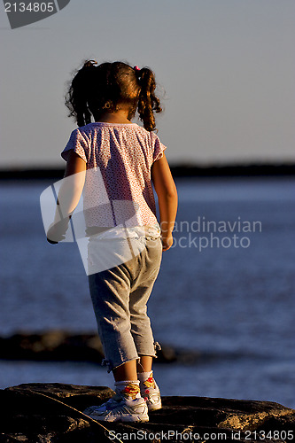 Image of little girl on the rock in the sunrise 