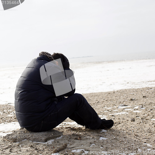 Image of Lonely man sitting on sand