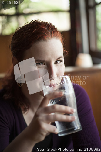 Image of Young Woman with Beautiful Auburn Hair Drinking Water