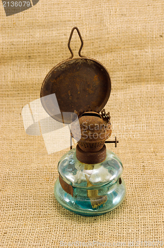 Image of rusty retro kerosene lamp burlap background 
