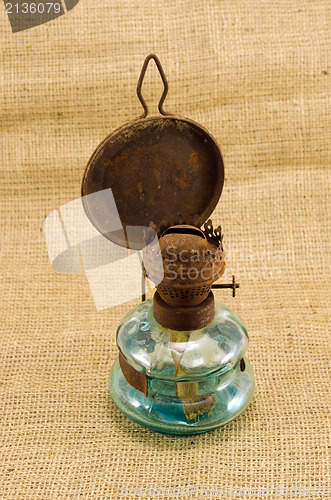 Image of rusty retro kerosene lamp burlap background 