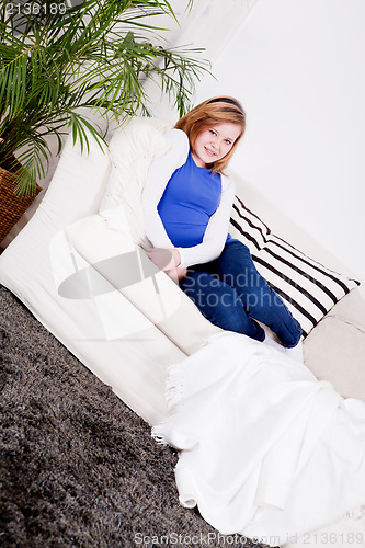 Image of happy teenager girl smiling sitting on couch 