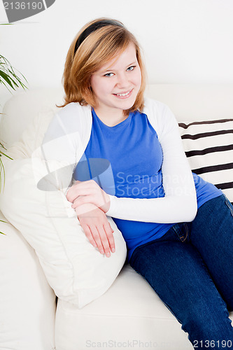 Image of happy teenager girl smiling sitting on couch 