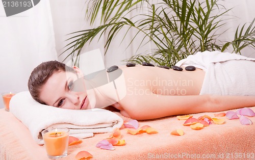 Image of young attractive woman get hot stone massage 