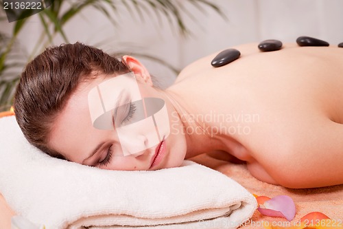 Image of young attractive woman get hot stone massage 