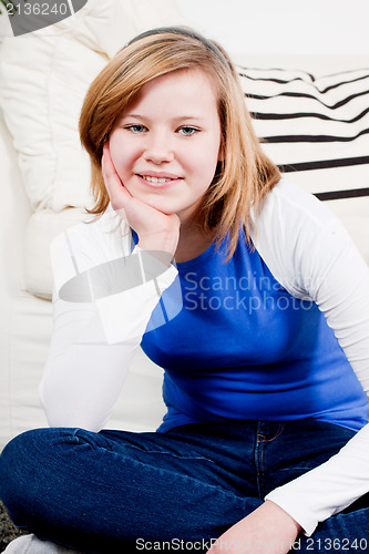 Image of happy teenager girl smiling sitting on couch 
