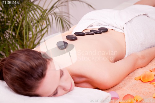 Image of young attractive woman get hot stone massage 