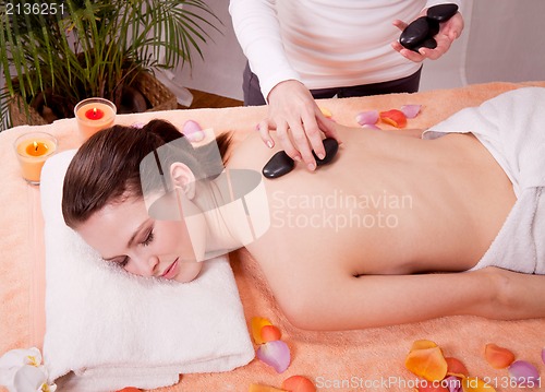 Image of young attractive woman get hot stone massage 