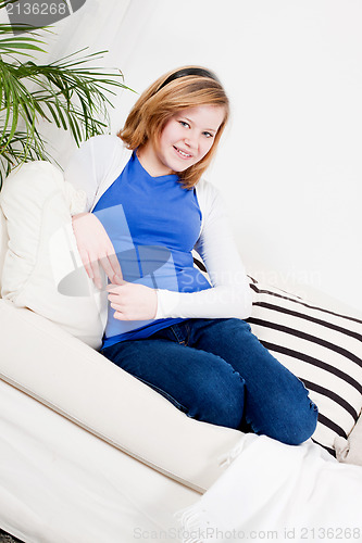 Image of happy teenager girl smiling sitting on couch 
