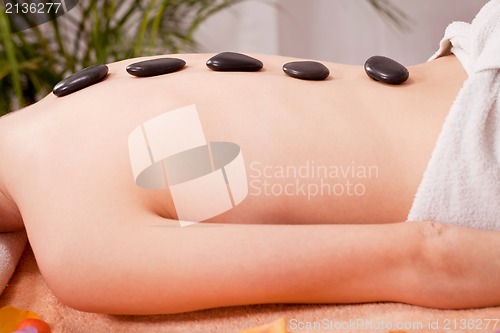 Image of young attractive woman get hot stone massage 