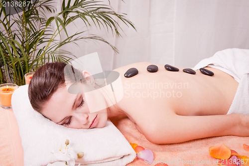 Image of young attractive woman get hot stone massage 