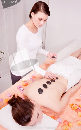 Image of young attractive woman get hot stone massage 