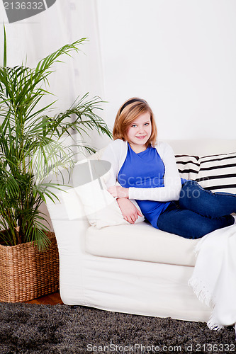 Image of happy teenager girl smiling sitting on couch 