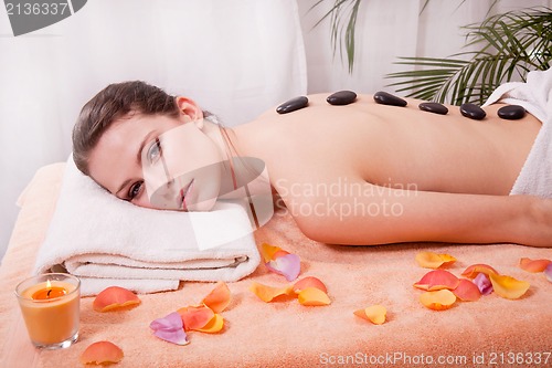 Image of young attractive woman get hot stone massage 