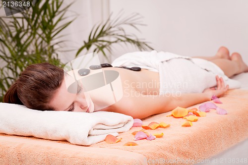 Image of young attractive woman get hot stone massage 