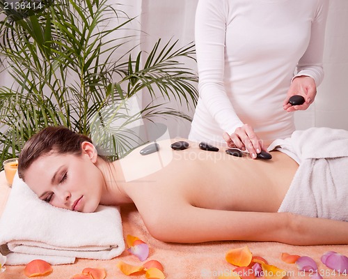 Image of young attractive woman get hot stone massage 