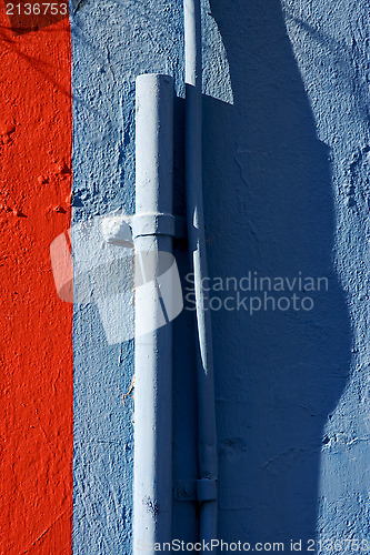 Image of blue colored pipe and red wall 