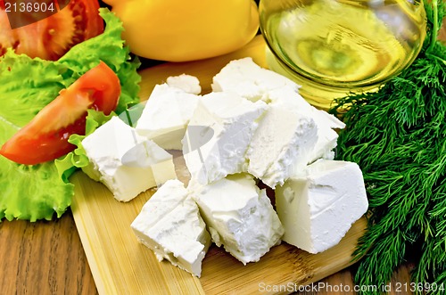 Image of Feta cheese on the board with vegetables and oil